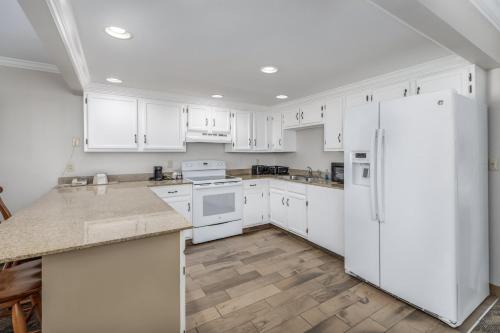 a kitchen with white cabinets and a white refrigerator at Crossroads Inn & Suites in Gatlinburg