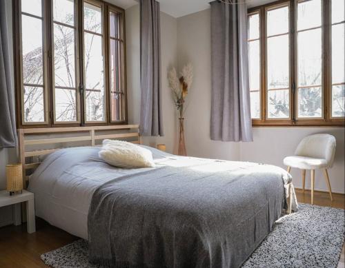 um quarto com uma cama, uma cadeira e janelas em Venez Chez Vous - Villa Magnolia em Annecy