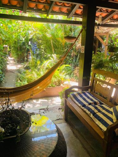 a hammock on a porch with a table and a chair at Pousada Tropicana in Abraão