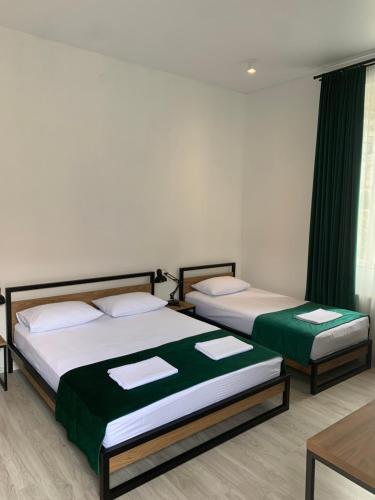 two beds in a room with green curtains at Polifonia Inn Borjomi in Borjomi