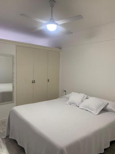 1 dormitorio blanco con 1 cama blanca y ventilador de techo en DPTO- 1 AMB ZONA TORREON- A METROS DEL MAR- en Mar del Plata