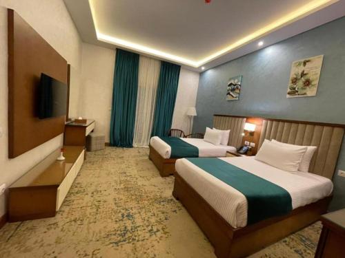 a hotel room with two beds and a television at Golden Jewel Ismailia Resort in Ismailia