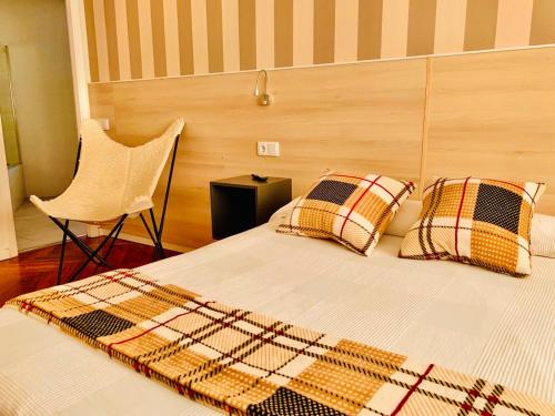 a bed with pillows and a chair in a room at Family & Groups Space, Santiago Center - No Kitchen in Santiago de Compostela