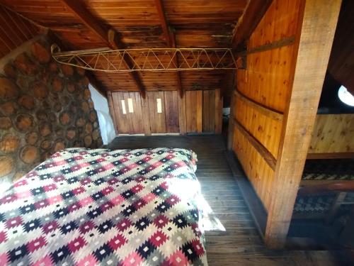 1 dormitorio con 1 cama en una cabaña de madera en Los Riscos Antigua Cabaña Toba en Loncopué