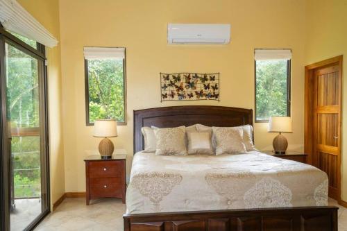 a bedroom with a large bed with two lamps and two windows at Vista Verde House w/Pool & WiFi in Paquita