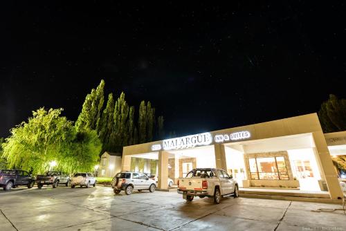 a store with cars parked in a parking lot at night at Hotel Malargue in Malargüe