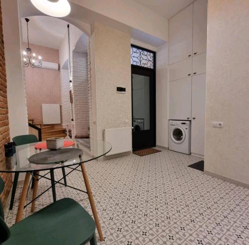 sala de estar con mesa de cristal y lavadora en Plexanovi Apart, en Tiflis