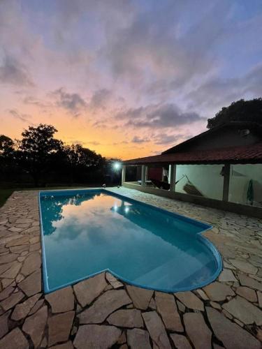 a blue swimming pool in front of a house at Chácara com Piscina in Araçoiaba da Serra