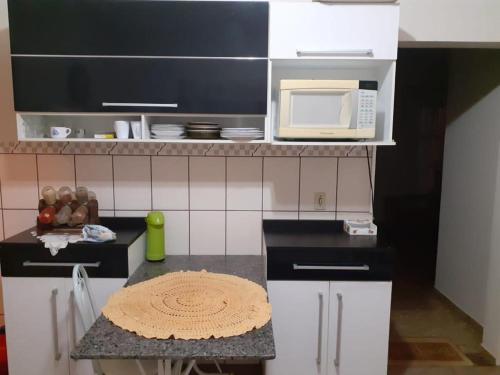 a small kitchen with a microwave and a table at Chácara com Piscina in Araçoiaba da Serra