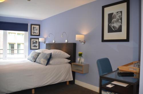 a bedroom with blue walls and a bed with a desk at Frisco Inn in Amsterdam