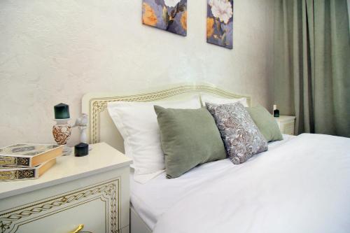 ein Schlafzimmer mit einem Bett mit weißen Laken und Kissen in der Unterkunft Уютная квартира в ЖК Адиет с видом на горы in Almaty