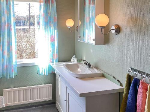 uma casa de banho com um lavatório, um espelho e uma janela em Holiday home ASKERSUND em Askersund