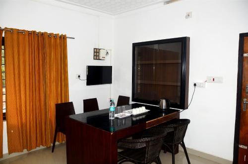 um quarto com uma mesa com cadeiras e uma televisão em Misty Ghats Resort em Wayanad