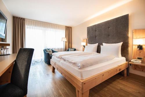 a hotel room with a large bed and a desk at Vitalpina Hotel Waldhof in Rablà