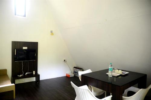 瓦亞納德的住宿－Misty Ghats Resort，一间用餐室,配有黑桌和白色椅子