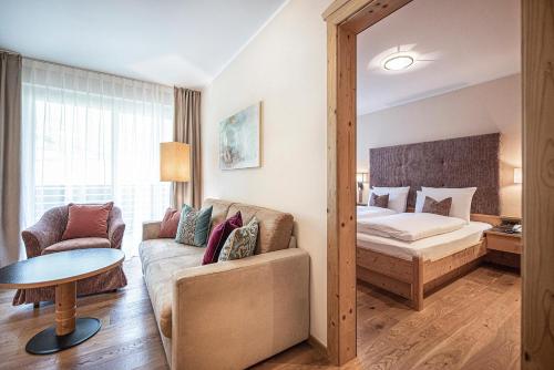 a living room with a couch and a bed in a room at Vitalpina Hotel Waldhof in Rablà