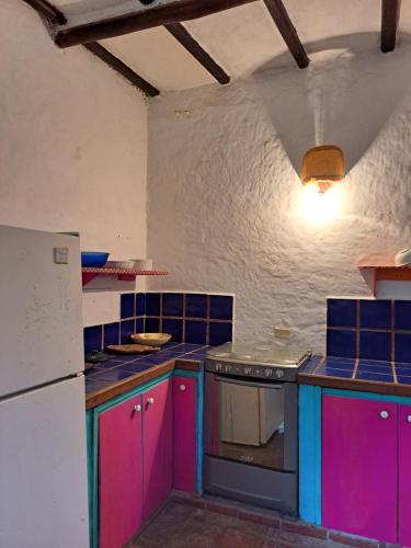 a kitchen with pink and blue cabinets and a refrigerator at La Casa del Mango in Pampatar