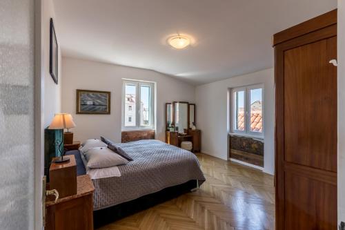 a bedroom with a bed and two windows at The Heart of Palace Apartment in Split