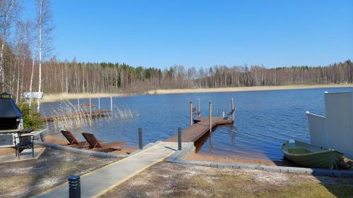 a dock with chairs and a boat on a lake at Arolahti Suite ( Rapojärvi ) in Kouvola