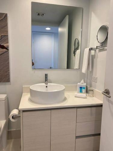 une salle de bain blanche avec un lavabo et un miroir dans l'établissement Just Minutes from the Beach, 2 Full Bed Studio, à Hallandale Beach