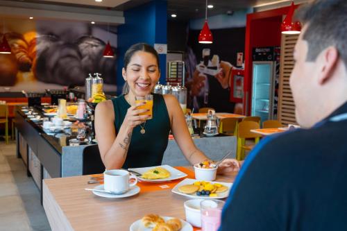 a woman sitting at a table with a glass of wine at ibis Trujillo in Trujillo