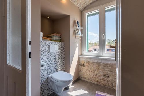 a bathroom with a toilet and a window at The Heart of Palace Apartment in Split