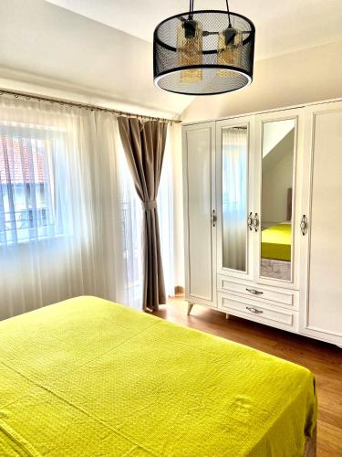 a bedroom with a green bed and a large window at M&M Center Apartment with free parking in Plovdiv
