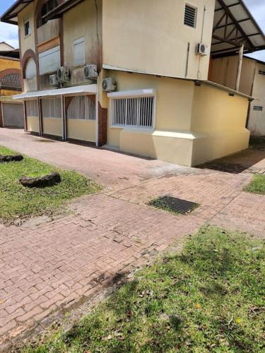 a building with a brick sidewalk in front of it at Hello-Guyane, Marina 2, Studio Prestige 5 étoiles in Saint-Laurent du Maroni