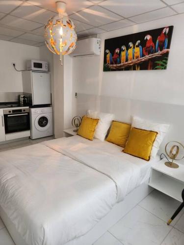 a white bedroom with a large bed with yellow pillows at Hello-Guyane, Marina 2, Studio Prestige 5 étoiles in Saint-Laurent du Maroni