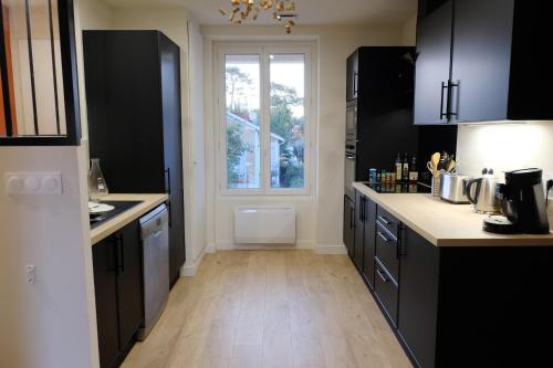 une cuisine avec des armoires noires et une fenêtre dans l'établissement Apt. moderne 6 pers, parking, 150m de la plage, à Saint-Georges-de-Didonne