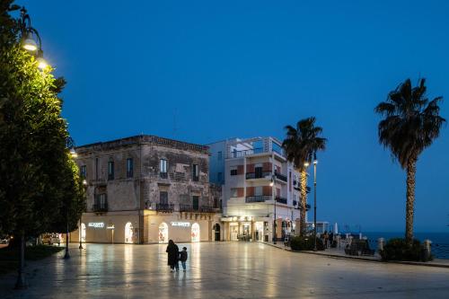 a building with palm trees in front of the ocean at Sofi' Center Rooms in Sciacca