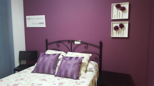アルカニスにあるApartamento Tinaの紫の壁のベッドルーム1室、紫の枕付きのベッド1台が備わります。