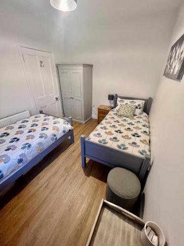 a small bedroom with two beds and a stool at The Blue Door in Kirkcudbright