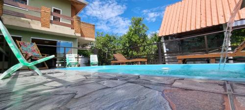 a patio with a swimming pool and a house at Recanto Dumar in Peruíbe