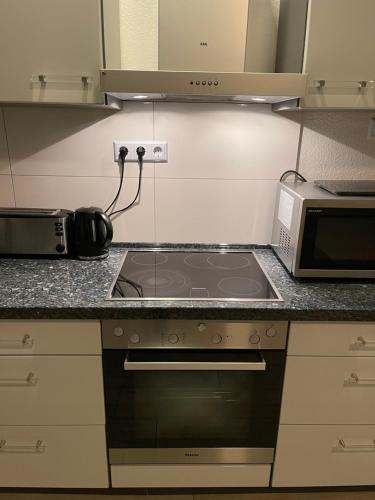 a kitchen with a stove top oven next to a microwave at Sweet Home Appartements in Bottrop