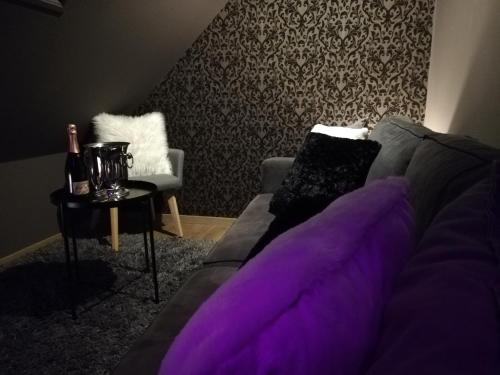 a living room with purple pillows on a couch at Love Room Alsace L'ESCALE DU DESIR - Balançoire d'amour, Croix de Saint André, Menottes et Fauteuil Tantra - CROISEE DES PARCS in Niederbronn-les-Bains
