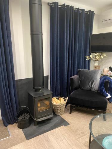 a living room with a wood stove and a chair at Balcony House Apartment in Kendal in Kendal
