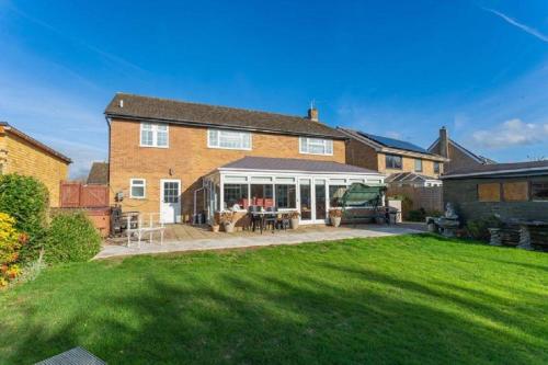a large brick house with a patio and a yard at Kennedy Villa - 5 Bedroom House with Hot Tub, WiFi, Free parkings, Close to Bicester Village in Bicester