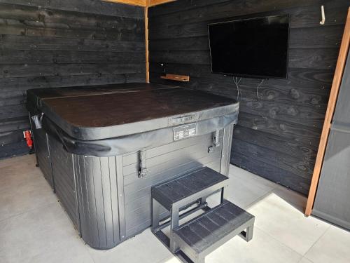a small stove in a room with a tv at Ham Annex met privé jacuzzi in Almelo