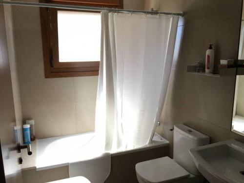 ein Bad mit einem weißen WC und einem Fenster in der Unterkunft Apartamento acogedor en la playa de La Lanzada in Sanxenxo