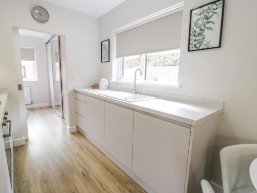 a white kitchen with a sink and a window at Peris Lodge in Caernarfon