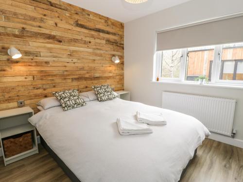 a bedroom with a large bed with a wooden wall at Peris Lodge in Caernarfon