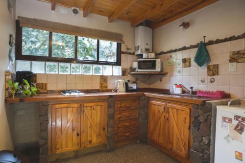 a kitchen with wooden cabinets and a window at El Colibrí Cabañas de la Naturaleza in Trelew