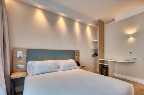 1 dormitorio con 1 cama blanca grande y escritorio en Holiday Inn Express - Madrid - Airport, an IHG Hotel en Madrid