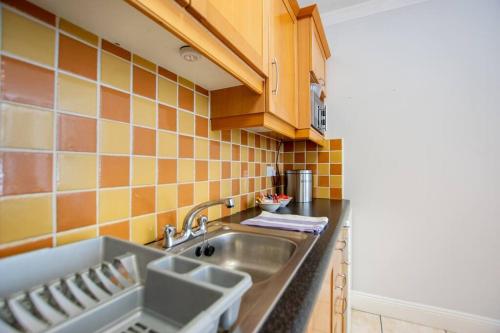 a kitchen with a sink and orange tiles on the wall at 106 - The Townhouse by Shortstays in Galway