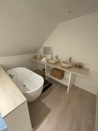 La salle de bains est pourvue d'une baignoire blanche et d'un lavabo. dans l'établissement Vakantieverblijf De Munt, à Oudenburg