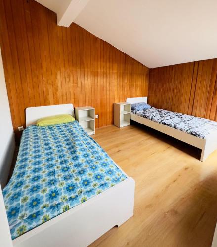 two beds in a room with wooden walls and wooden floors at Pension Asel in Wörth am Rhein