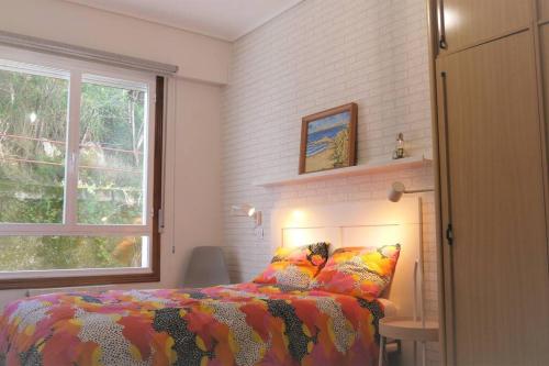 um quarto com uma cama com um edredão colorido e uma janela em AMANE Lekeitio, Parking Incluido em Lekeitio