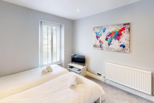 a white bedroom with a bed and a tv at CROYDE BRIAR HOUSE 4 Bedrooms in Croyde