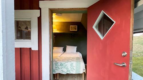 a red door leading into a bedroom with a bed at STF Tivedstorp in Tivedstorp